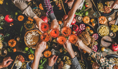 Family celebrating Thanksgiving day. Flat-lay of feasting peoples hands clinking glasses with rose...