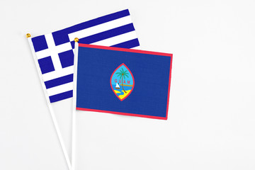 Guam and Greece stick flags on white background. High quality fabric, miniature national flag. Peaceful global concept.White floor for copy space.