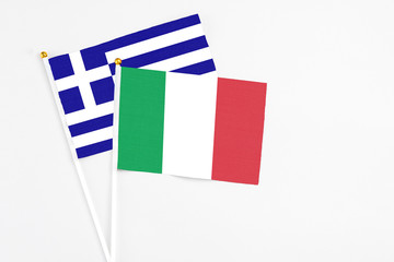 Fototapeta na wymiar Italy and Greece stick flags on white background. High quality fabric, miniature national flag. Peaceful global concept.White floor for copy space.