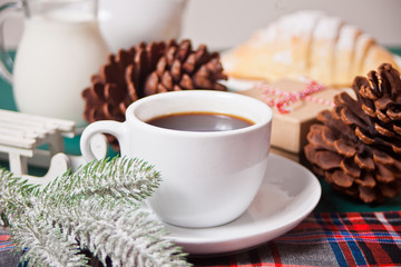 Cup of coffee, homemade bun croissant and Christmas decoration.