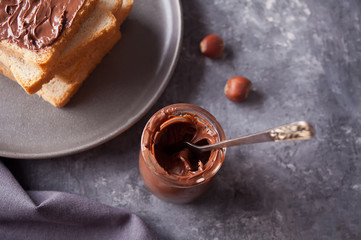 Bread toast with chocolate cream butter, jar of chocolate cream on the concrete background