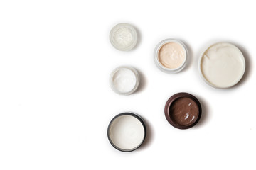 Care products for face, hands and body. Cream in jars on white background. Space for text