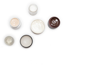 Care products for face, hands and body. Cream in jars on white background. Space for text