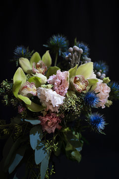 Beautiful wedding bouquet with green Cymbidium, eringium, eustoma on a black background. Copy space.