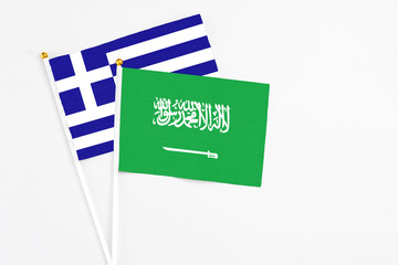 Saudi Arabia and Greece stick flags on white background. High quality fabric, miniature national flag. Peaceful global concept.White floor for copy space.