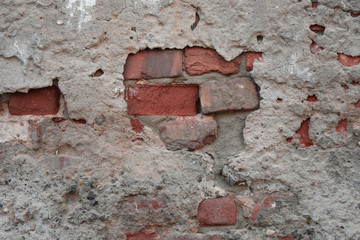 Old ruined wall with sticking out fragments of red bricks and cement in hole