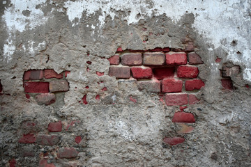 Old ruined wall with sticking out fragments of red bricks and cement - horizontal