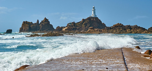 La Corbiere Leuchtturm auf Jersey bei Flut und Sonnenschein mit Wellengang