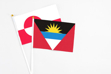 Antigua and Barbuda and Greenland stick flags on white background. High quality fabric, miniature national flag. Peaceful global concept.White floor for copy space.