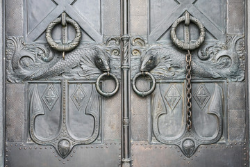 door handles in the form of a fish with a ring in his mouth on a metal door in the historic part of Kronshtadt, Russia