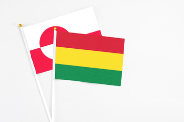 Bolivia and Greenland stick flags on white background. High quality fabric, miniature national flag. Peaceful global concept.White floor for copy space.