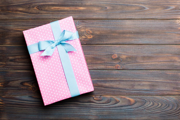 paper gift box with colored ribbon on dark wood background. top view with copy space Christmas...