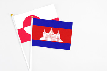 Cambodia and Greenland stick flags on white background. High quality fabric, miniature national flag. Peaceful global concept.White floor for copy space.