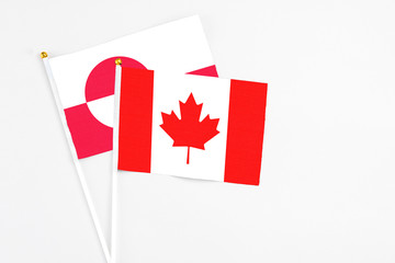 Canada and Greenland stick flags on white background. High quality fabric, miniature national flag. Peaceful global concept.White floor for copy space.