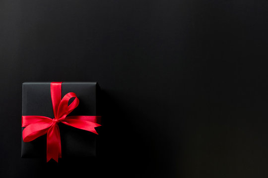 Top view of black christmas gift boxes with red ribbon on black background with copy space for text., black friday advertisement.