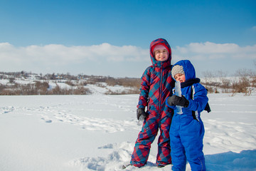 Fototapeta na wymiar Happy brother and sister play on a winter walk, making snowballs in the park. Winter outdoor games.