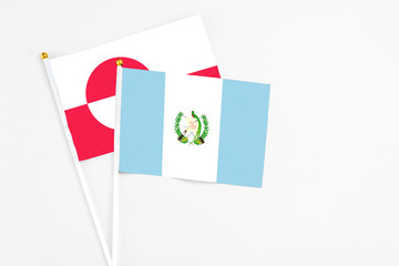 Guatemala and Greenland stick flags on white background. High quality fabric, miniature national flag. Peaceful global concept.White floor for copy space.