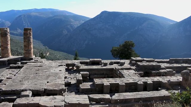 Panoramic view of the ruins of the ancient temple of Apollo at Delphi Sanctuary, Phocis Greece, with mountain landscape in background.