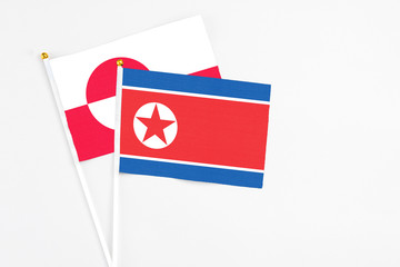 North Korea and Greenland stick flags on white background. High quality fabric, miniature national flag. Peaceful global concept.White floor for copy space.