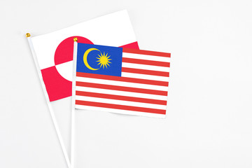 Malaysia and Greenland stick flags on white background. High quality fabric, miniature national flag. Peaceful global concept.White floor for copy space.