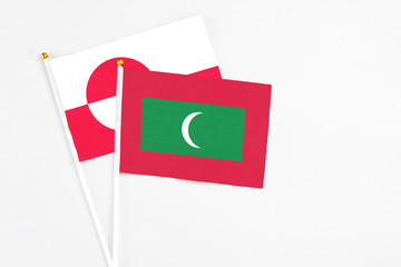 Maldives and Greenland stick flags on white background. High quality fabric, miniature national flag. Peaceful global concept.White floor for copy space.