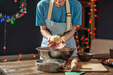 Young woman makes dough for cooking festive ginger cookies. Cozy home atmosphere in the evening on Christmas eve