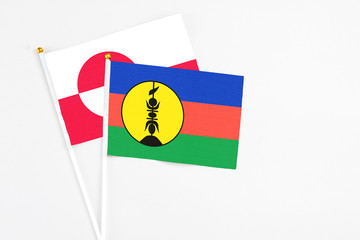 New Caledonia and Greenland stick flags on white background. High quality fabric, miniature national flag. Peaceful global concept.White floor for copy space.