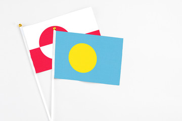 Palau and Greenland stick flags on white background. High quality fabric, miniature national flag. Peaceful global concept.White floor for copy space.