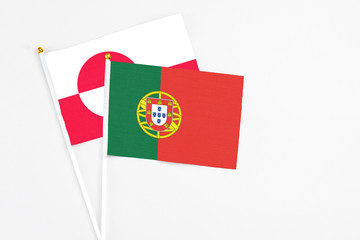 Portugal and Greenland stick flags on white background. High quality fabric, miniature national flag. Peaceful global concept.White floor for copy space.