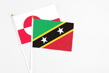 Saint Kitts And Nevis and Greenland stick flags on white background. High quality fabric, miniature national flag. Peaceful global concept.White floor for copy space.