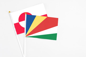 Seychelles and Greenland stick flags on white background. High quality fabric, miniature national flag. Peaceful global concept.White floor for copy space.