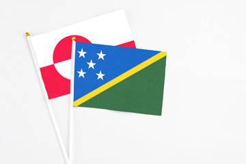 Solomon Islands and Greenland stick flags on white background. High quality fabric, miniature national flag. Peaceful global concept.White floor for copy space.