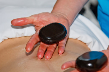 Wellness concept. Handsome young man relaxing under the stimulating effect of a traditional hot stone massage in a luxury spa and wellness center. Recovery after work.