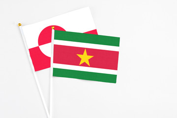 Suriname and Greenland stick flags on white background. High quality fabric, miniature national flag. Peaceful global concept.White floor for copy space.