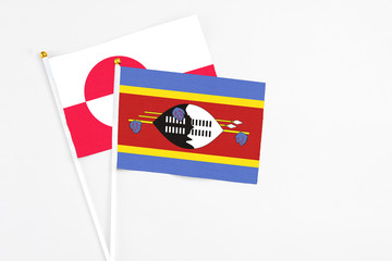 Swaziland and Greenland stick flags on white background. High quality fabric, miniature national flag. Peaceful global concept.White floor for copy space.