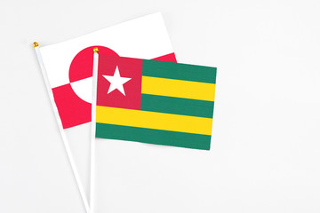 Togo and Greenland stick flags on white background. High quality fabric, miniature national flag. Peaceful global concept.White floor for copy space.