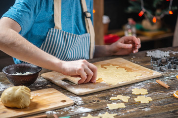 Woman rolls out the dough with a rolling pin and shapes gingerbread. Christmas mood for cooking...