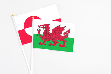 Wales and Greenland stick flags on white background. High quality fabric, miniature national flag. Peaceful global concept.White floor for copy space.
