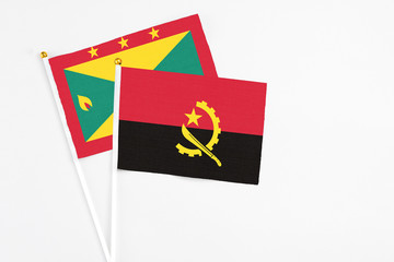 Angola and Grenada stick flags on white background. High quality fabric, miniature national flag. Peaceful global concept.White floor for copy space.