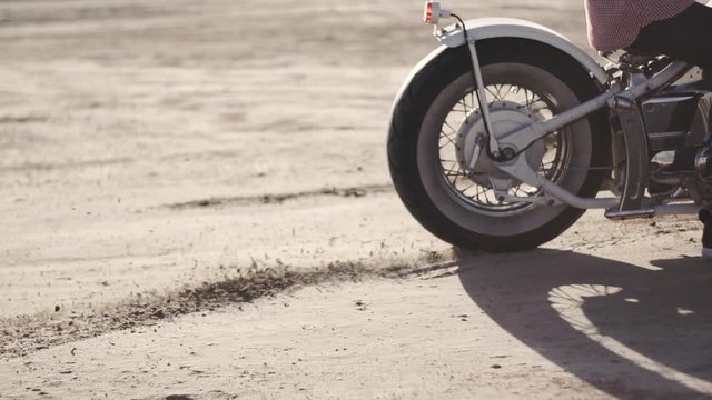 Motorcyclist doing tire burnout in the desert, slow motion. Professional motorcyclist drift and turns on a motorcycle on the ground, a biker does a trick on a motorcycle