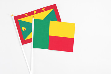 Benin and Grenada stick flags on white background. High quality fabric, miniature national flag. Peaceful global concept.White floor for copy space.