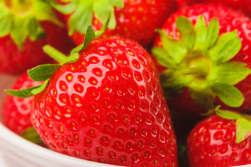 Red ripe strawberry in the white bowl, light background