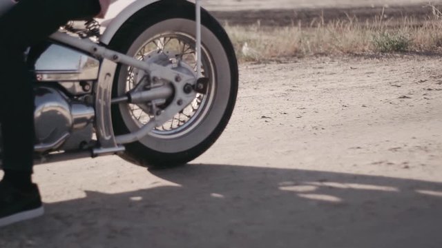 Motorcyclist doing tire burnout in the desert, slow motion. Professional motorcyclist drift and turns on a motorcycle on the ground, a biker does a trick on a motorcycle