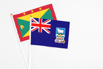 Fototapeta premium Falkland Islands and Grenada stick flags on white background. High quality fabric, miniature national flag. Peaceful global concept.White floor for copy space.