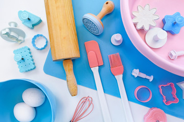 Top view flat lay with cute pink and blue baking utensils like baking mat, wooden rolling pin,...