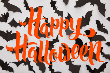 top view of paper black bats on white background with red happy Halloween illustration