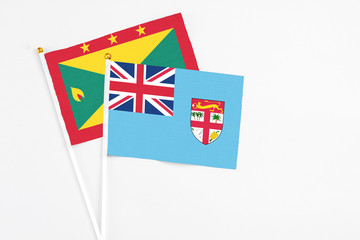 Fiji and Grenada stick flags on white background. High quality fabric, miniature national flag. Peaceful global concept.White floor for copy space.