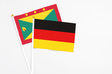 Germany and Grenada stick flags on white background. High quality fabric, miniature national flag. Peaceful global concept.White floor for copy space.