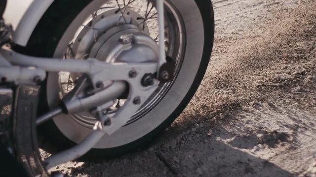 Motorcyclist doing tire burnout in the desert, slow motion. Professional motorcyclist drift and turns on a motorcycle on the ground, a biker does a trick on a motorcycle