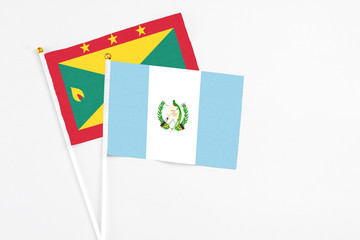 Guatemala and Grenada stick flags on white background. High quality fabric, miniature national flag. Peaceful global concept.White floor for copy space.